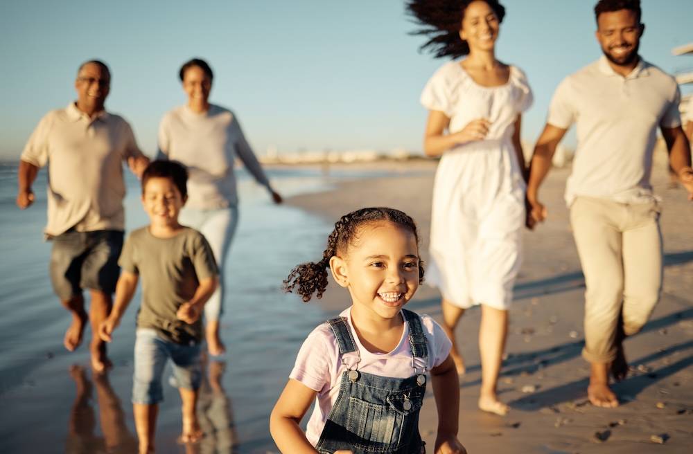 Family with children, parents, and grandparents walking down a beach