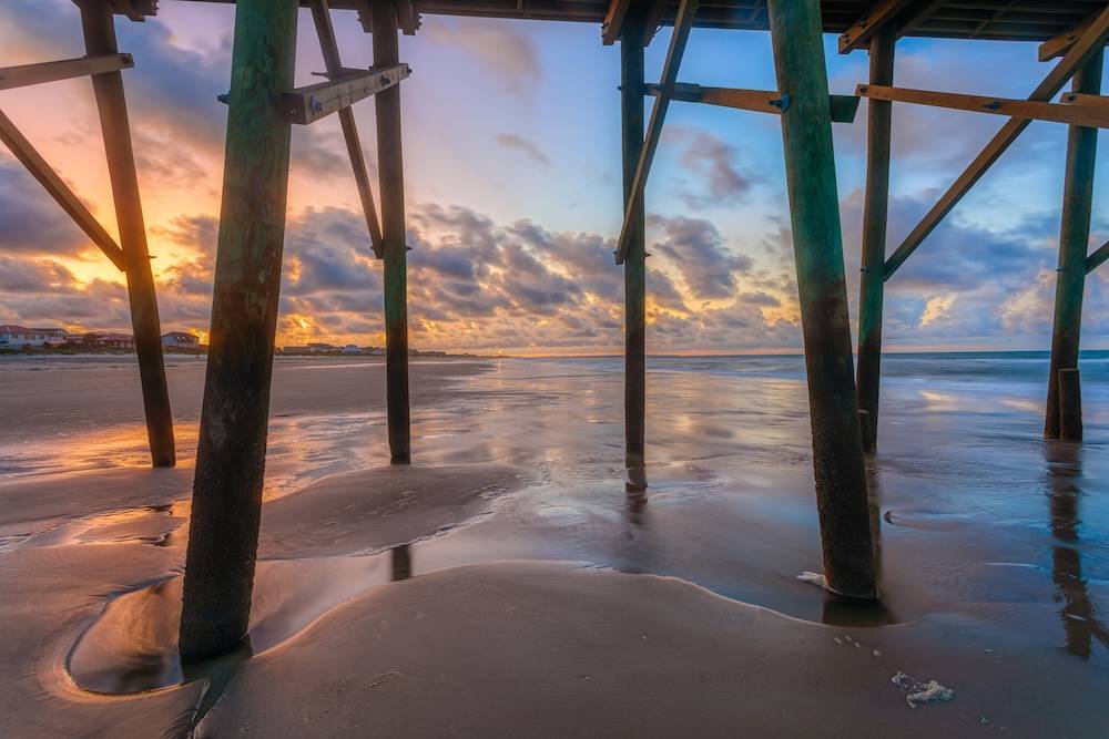 Sand and ocean viewed from underneath the Oak Island pier