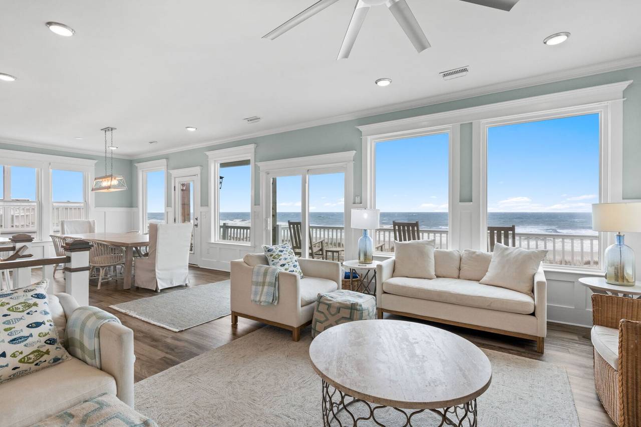 Vacation rental interior with high ceilings, large windows, and ocean views