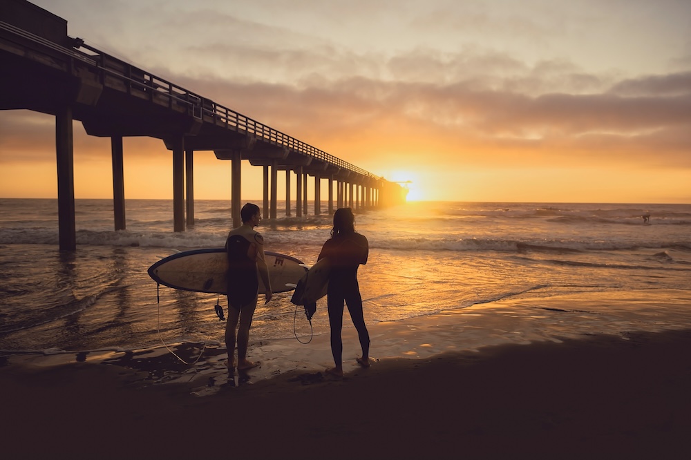 friends surfing near the pier