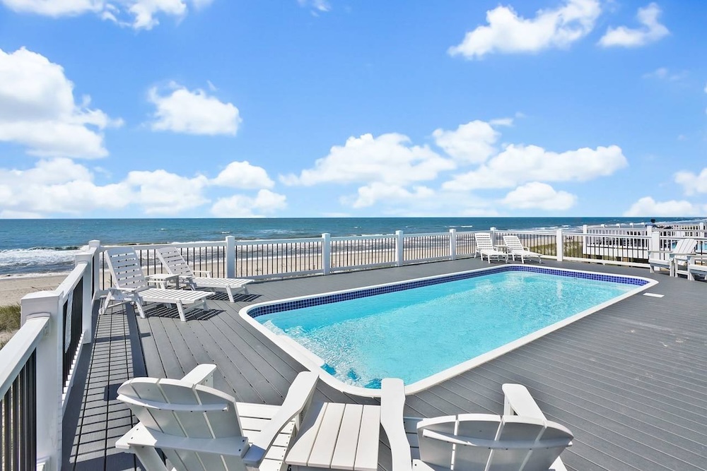 Pool deck of a vacation rental with beach and ocean view in background