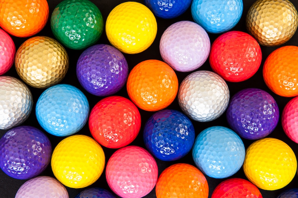 Several mini golf balls of various colors against a black background