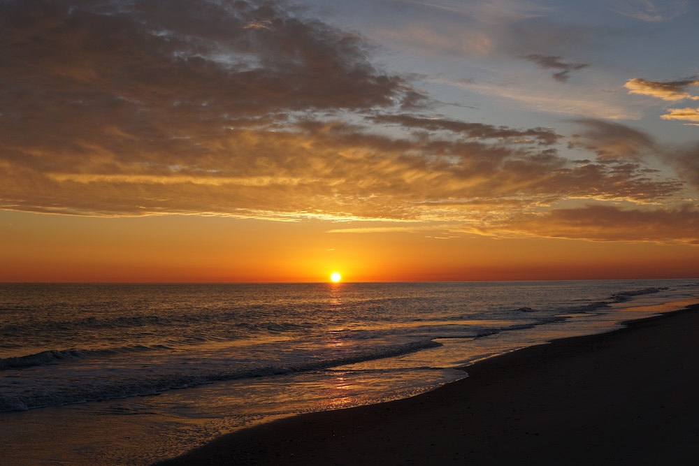 Beach with ocean and sunset in background