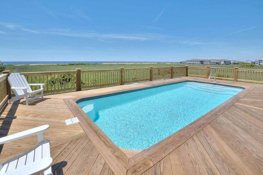 Pool deck of a vacation rental with marshland and ocean view in background