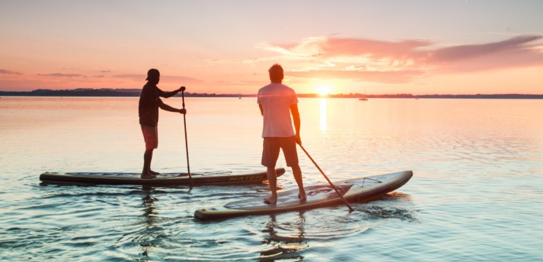 two men learning stand up paddle boarding | Better Beach Rentals