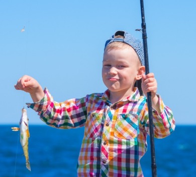 little boy holding fish he caught on the pier | Better Beach Rentals